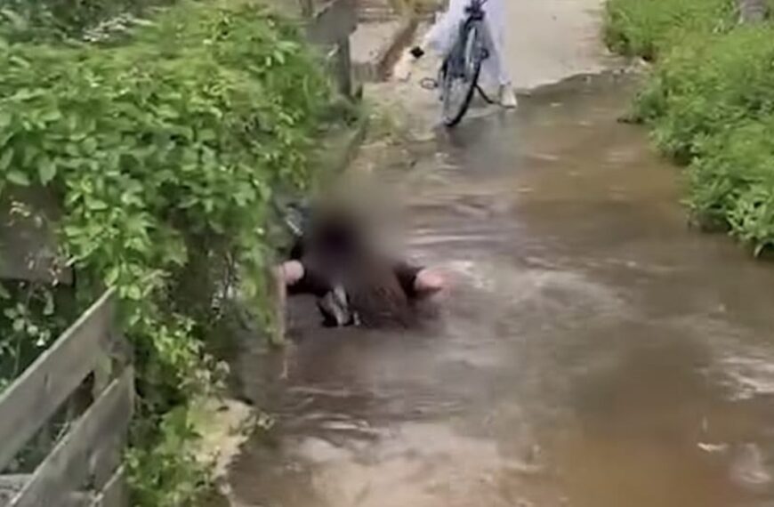 Meisje fietst door grote plas en verdwijnt plotseling bijna volledig onder water